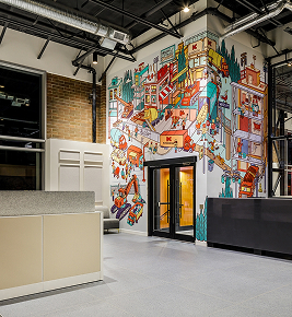 Modern office lobby with colorful mural on wall, depicting a lively cityscape and various buildings.